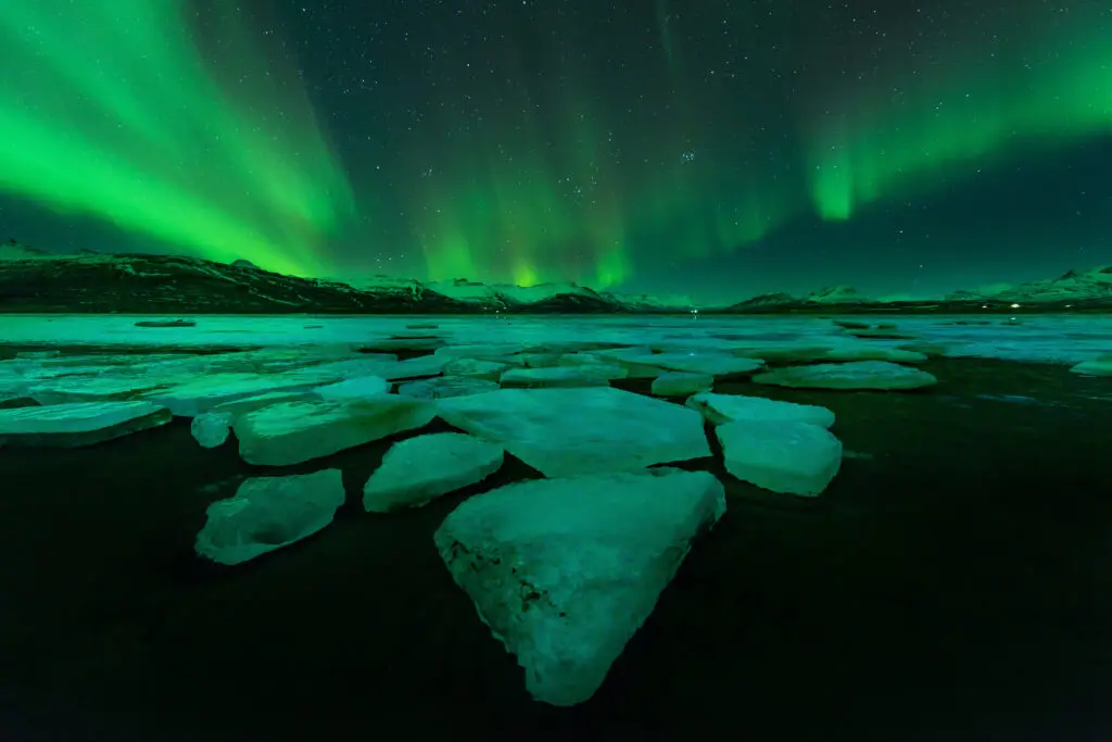 Vibrant Northern Lights over icy landscape in Iceland, a stunning natural phenomenon and popular tourist attraction.