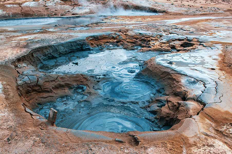 Vivid geothermal pools and mud pots at Hverir, Iceland, showcasing vibrant mineral-rich earth and steaming vents.