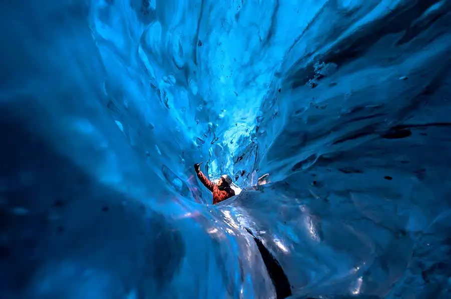 Tourist exploring the magnificent blue ice cave in Iceland during a private guided tour.