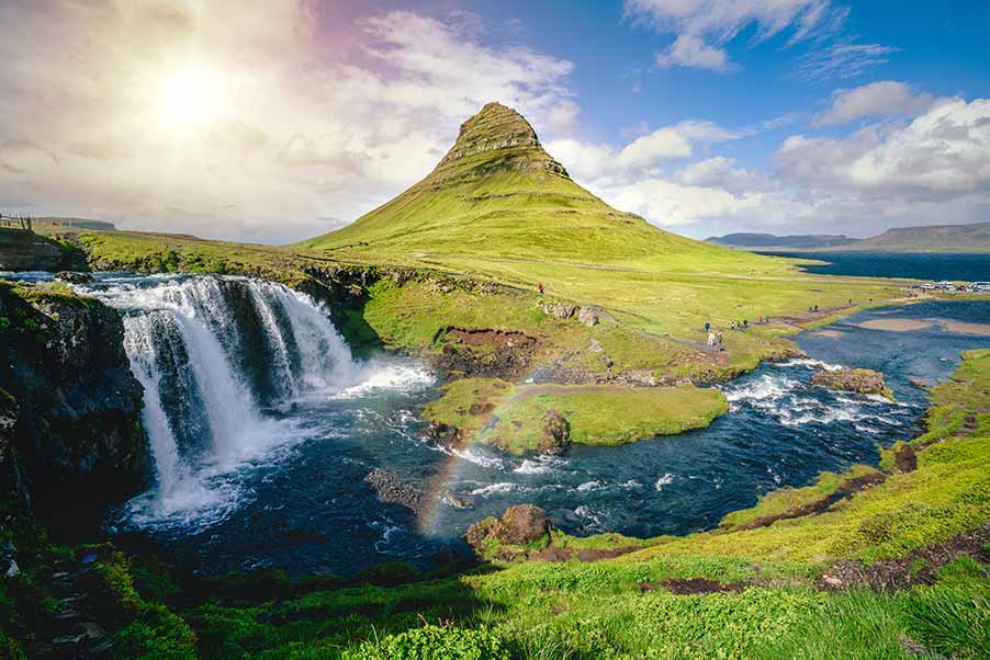 Iconic view of Kirkjufell mountain and waterfall in Iceland, a popular destination for tourists and photographers.