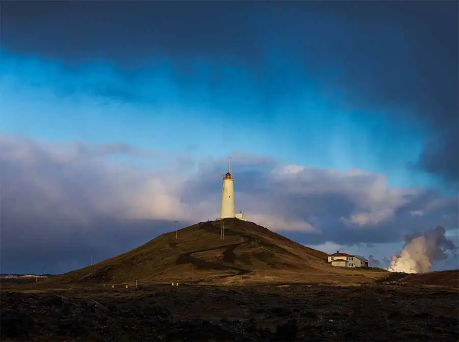 Reykjanes Lighthouse in Iceland standing on a grassy hill under a dramatic sky, a popular tourist attraction in Scandinavia.