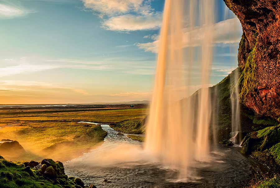 Seljalandsfoss Waterfall in Iceland at sunset with flowing water and vibrant landscape, a popular tourist attraction perfect for private tours.
