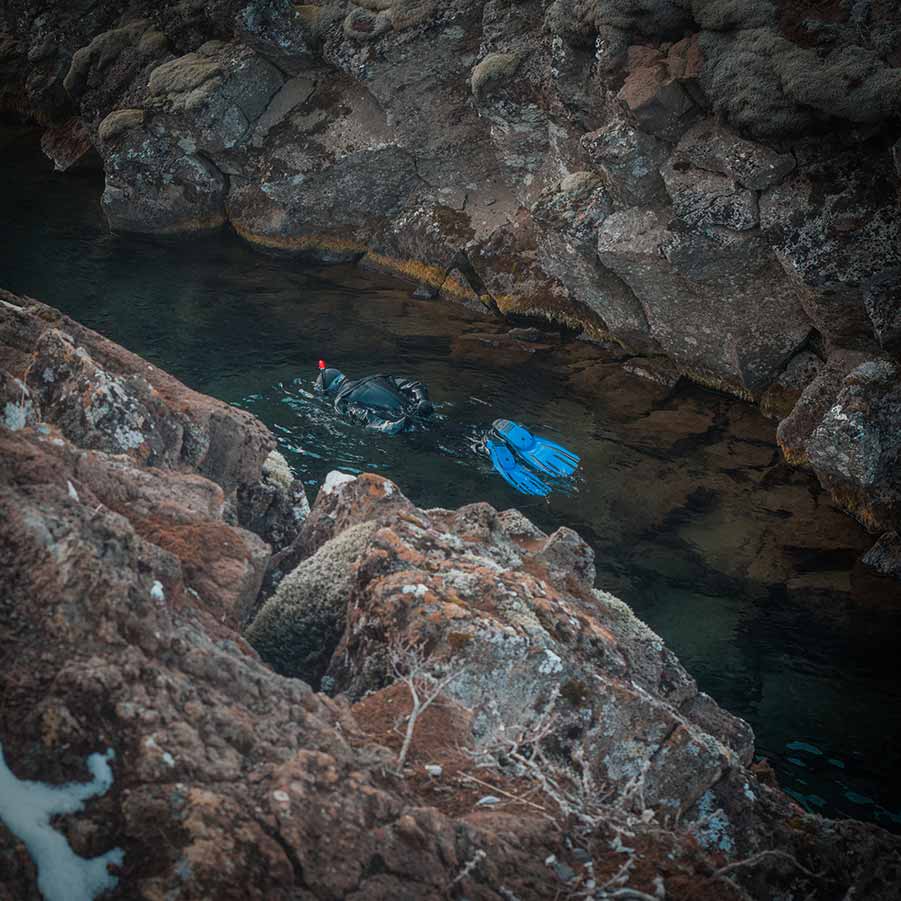 Scuba divers exploring the clear waters of the Silfra Fissure in Þingvellir National Park, Iceland, a popular spot for diving between tectonic plates.