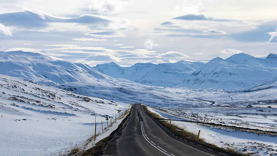 Scenic view of Skagafjörður Valley Road in Iceland, showcasing a winding road through snowy landscapes with distant mountains under a bright sky, ideal for Nordic road trips and sightseeing in Scandinavia.