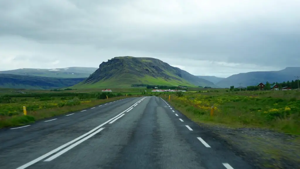 Scenic view of Hvalfjörður with lush green landscape and open road in Southwest Iceland, ideal for exploring Icelandic nature and geography.