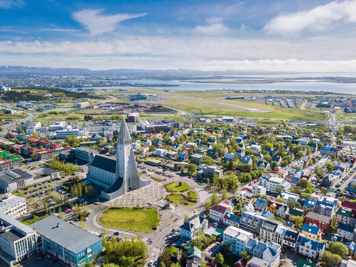 Aerial view of Reykjavik cityscape showing Hallgrimskirkja church and surrounding colorful buildings, illustrating the vibrant urban layout and architectural landmarks of Iceland's capital.