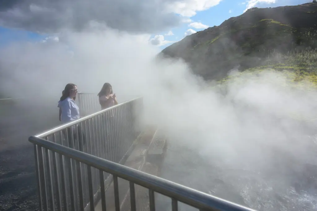 Tourists enjoying the steamy atmosphere at Deildartunguhver Hot Springs, a popular geothermal attraction in Iceland.