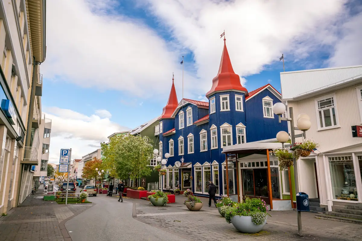 Colorful vintage buildings with distinctive red rooftops in downtown Akureyri, Iceland, showcasing local architecture and vibrant urban life.