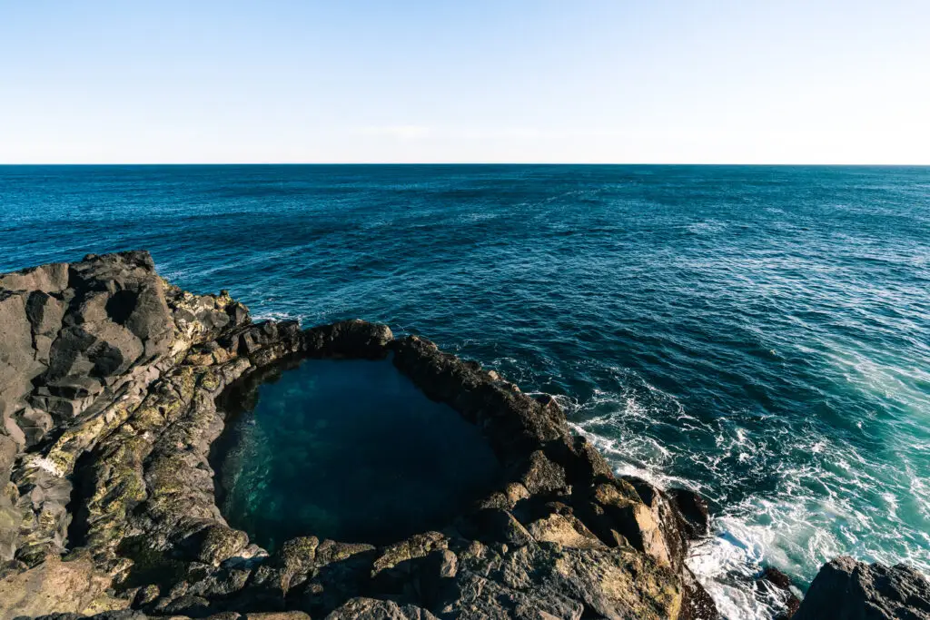 Brimketill lava rock pool on Reykjanes Peninsula, Iceland, a captivating natural attraction formed by volcanic activity, overlooking the vibrant blue ocean.